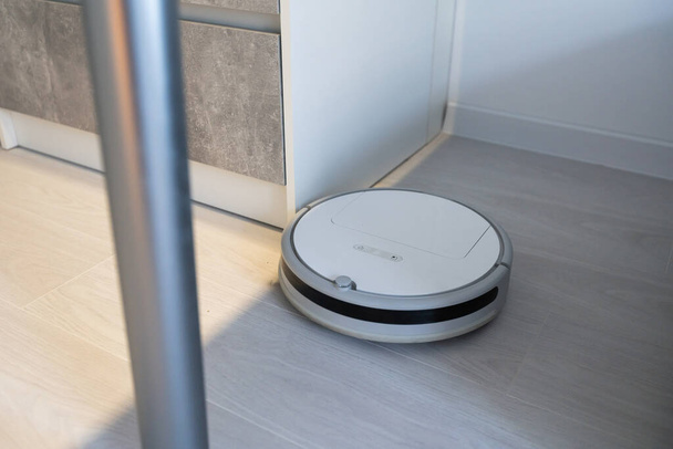 Modern robotic vacuum cleaner on floor in living room. Space for text - Photo, Image