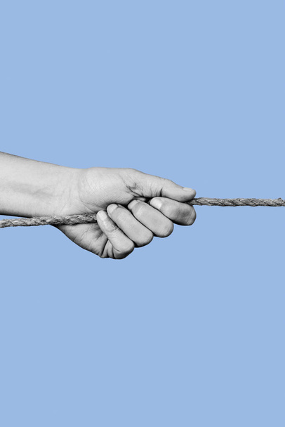 a young man pulls a rope in black and white, on a blue background - Photo, Image