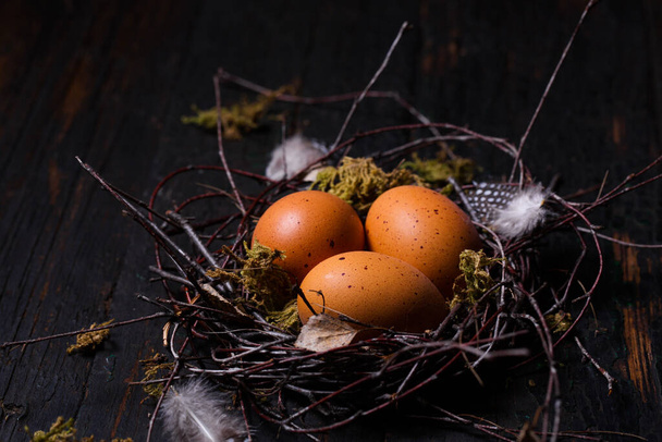 Schöne Ostereier in einem Nest auf Holzgrund. Osterkonzept im rustikalen Stil - Foto, Bild