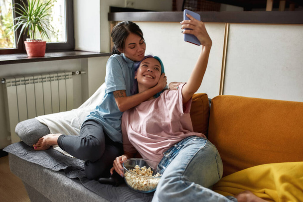 Lovely lesbian couple taking selfie in living room - Photo, image