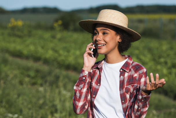 sorrindo mulher americana africana em chapéu de palha falando no smartphone ao ar livre - Foto, Imagem