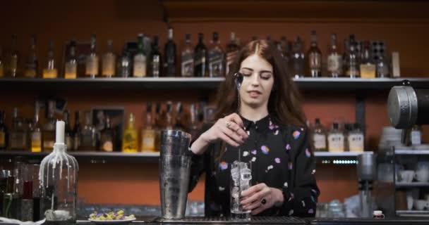 Ragazza rossa Giovane donna adulta barista prepara miscele cocktail sanguinosa mery al bar - Filmati, video