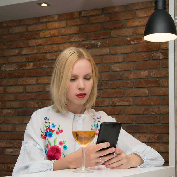 Woman with a glass of wine and a phone. - Zdjęcie, obraz