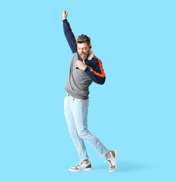 Cool dancing and singing young man on color background - Zdjęcie, obraz