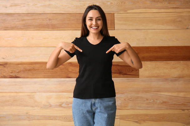 Молодая женщина в пустой футболке на деревянном фоне - Фото, изображение