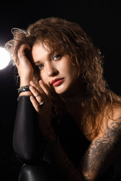 Όμορφη μοντέρνα γυναίκα με τατουάζ σε μαύρο φόντο - Φωτογραφία, εικόνα