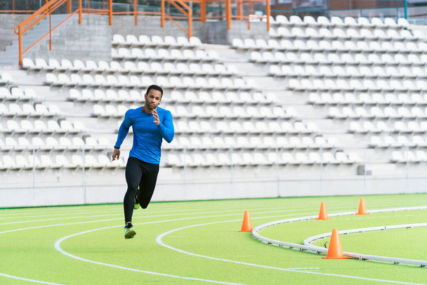 Black man running on a track. - Zdjęcie, obraz