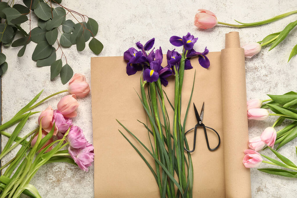 Composition avec de belles fleurs printanières, ciseaux et papier d'emballage sur fond clair - Photo, image