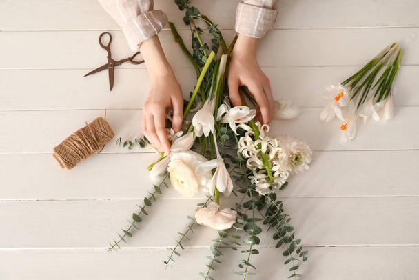 Mãos femininas com flores bonitas, corda e tesoura em fundo de madeira leve - Foto, Imagem