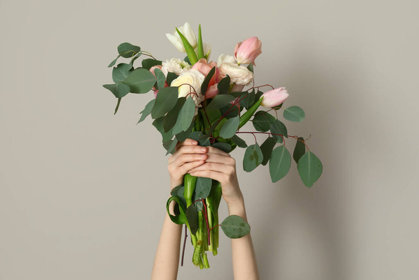 Mains féminines avec beau bouquet sur fond gris - Photo, image