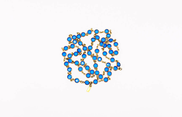 Golden chain with blue stones. Beads isolated on white. - Foto, Imagen
