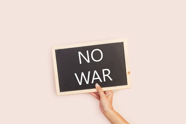 Woman hand holding a blackboard with no war word write on it - Photo, Image