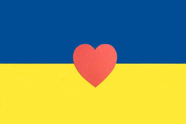 Un corazón de papel rojo en una bandera ucraniana - Foto, imagen