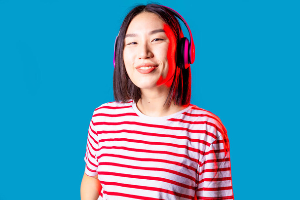 portrait young asiatic woman isolated background listening music with wireless headphones smiling positive and confident - Photo, Image