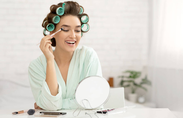 Lady With Curlers Making Makeup Applying Eye Shadow In Bedroom - Foto, Imagem