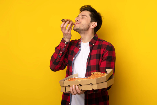 Happy Guy Holding Box Biting Pizza At Studio - 写真・画像