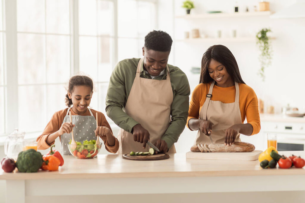 Familia africana feliz cocina cortar verduras y pan en la cocina - Foto, Imagen