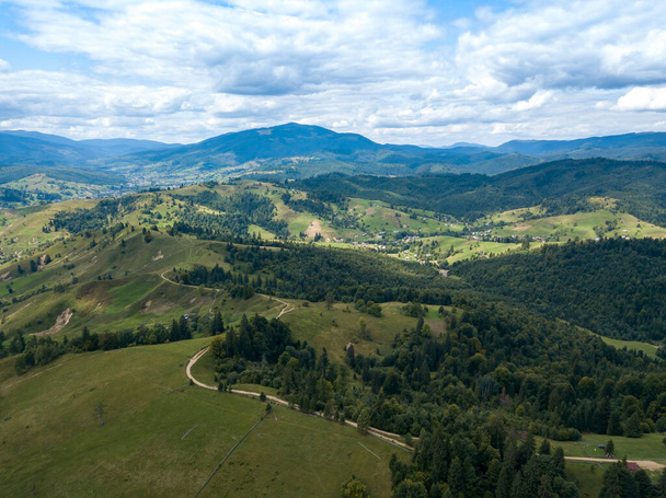 Green mountains of Ukrainian Carpathians in summer. Coniferous trees on the slopes. Aerial drone view. - Foto, afbeelding