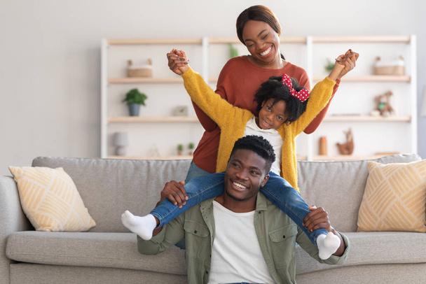 Hogar divertido. alegre afro-americana familia de tres engañando en sala de estar - Foto, imagen