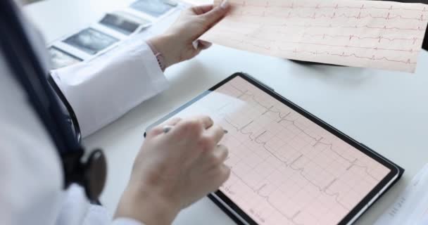 Kardiolog bada elektrokardiogram pacjenta w tabletkach - Materiał filmowy, wideo