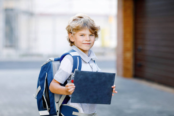 Happy little kid boy with backpack or satchel called Ranzen in German. Schoolkid on the way to school. Healthy adorable child outdoors On desk First day second grade in German. Back to school. - Photo, Image