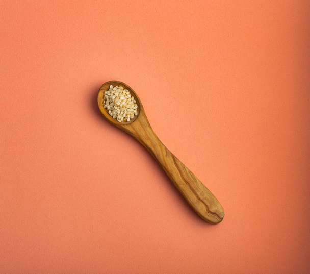 Organic sesame seeds in the wooden spoon - Sesamum indicum - Fotó, kép
