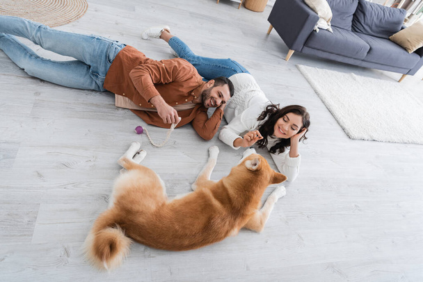 junges Paar liegt mit Akita-Hund auf dem Boden - Foto, Bild