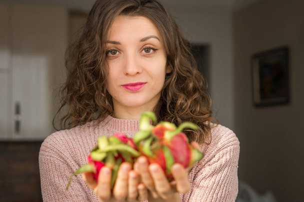 Chica joven está sosteniendo dos frutas frescas de dragón orgánico maduro o pitaya, pitahaya. Frutas exóticas, concepto de alimentación saludable - Foto, Imagen