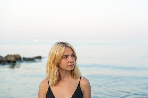 Jonge blonde vrouw op een rotsachtige kust na zonsondergang. Odessa. Oekraïne - Foto, afbeelding