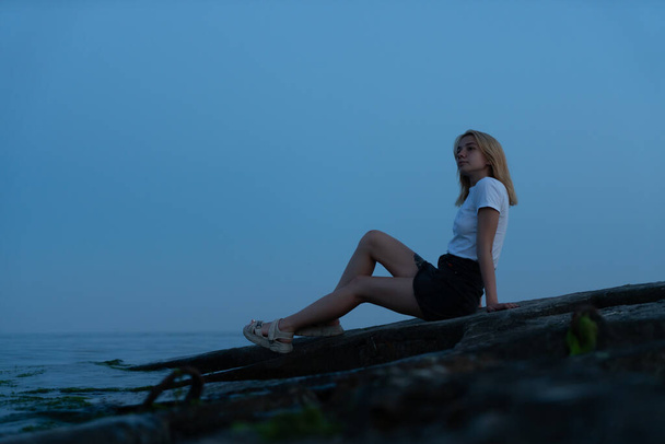 Молодая блондинка на скалистом побережье после заката. Одесса. Украина - Фото, изображение