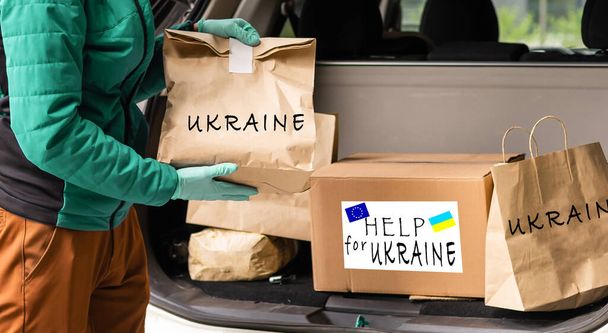Primo piano del cyrrying box volontario con l'aiuto umanitario per i rifugiati ucraini in strada - Foto, immagini