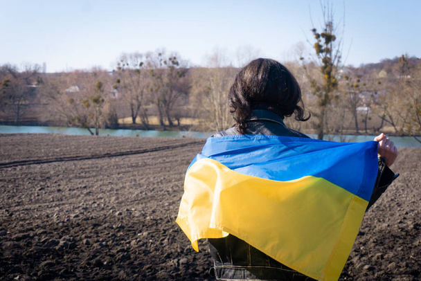 フィールドのウクライナの旗で覆われた若い男。愛国者 - 写真・画像