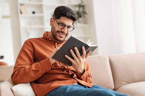 Fiatal arab férfi szemüvegben könyvet olvas - Fotó, kép