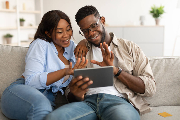 Black couple having videocall using tablet waving hands - Fotó, kép