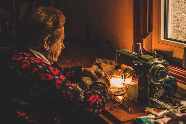 femme couture machine devant une fenêtre pour profiter de la lumière - Photo, image