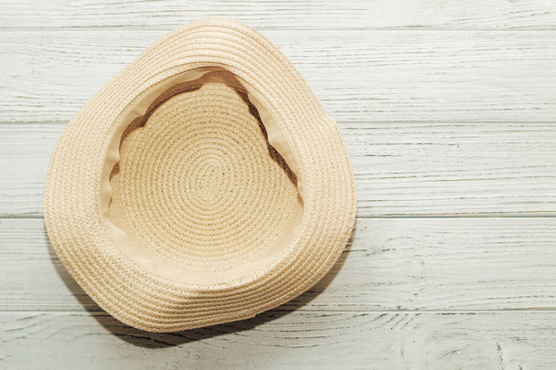 Ψάθινο κίτρινο καπέλο με ανώμαλο χείλος σε ξύλινο φόντο. - Φωτογραφία, εικόνα