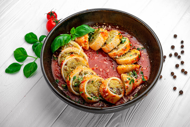 Wypchane kalmary. Kalmary nadziewane ryżem i warzywami w sosie pomidorowym, gotowane w sosie pomidorowym i winnym - Zdjęcie, obraz