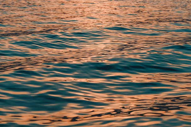 Rippled surface of blue sea water in sunset, orange and teal tones, selective focus - Foto, immagini