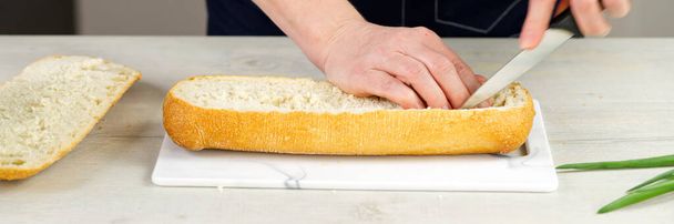 the cook cuts fresh ciabatta bread. Pulls out the pulp from the inside. Makes a base for stuffing bread. huge sandwich making process. - Foto, Imagen