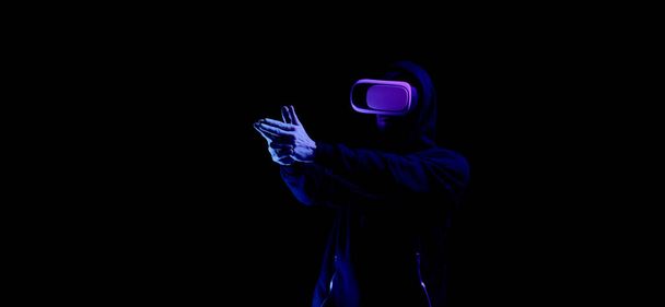 Virtual reality spel vr. Jongeman in digitale bril voor virtual reality technologie geïsoleerd op donkere neon achtergrond. Studie en virtuele wereld in 3D simulatie - Foto, afbeelding