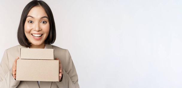 Femme d'affaires asiatique enthousiaste, donnant des boîtes de commande client, debout sur fond blanc - Photo, image