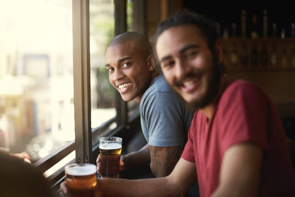 Enjoying a pint with his mates. Portrait of two friends enjoying themselves in the pub. - Foto, Bild