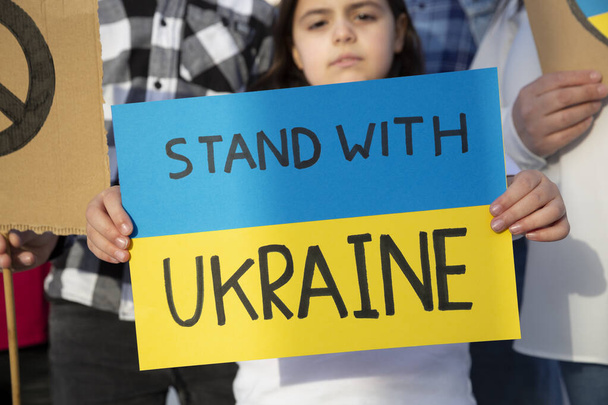 Niño pequeño sosteniendo un cartel con un mensaje de apoyo para el pueblo ucraniano. Manifestación contra la guerra. Ucrania libre. - Foto, imagen
