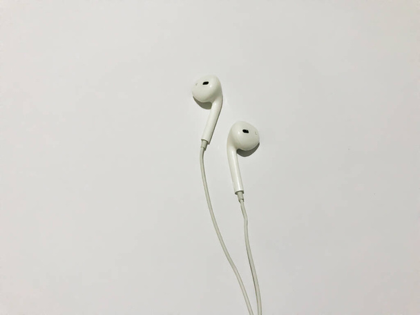 Λευκό ακουστικό απομονωμένο σε λευκό φόντο με φόντο αντίγραφο χώρου. λευκά μοντέρνα ακουστικά με ακουστικά σε ανοιχτό γκρι φόντο. έννοια της ψηφιακής μουσικής - Φωτογραφία, εικόνα