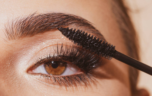 Eyebrow makeup. Macro close up of brows. Woman brushing brows with brows brush closeup. Natural beauty brows. - Фото, зображення