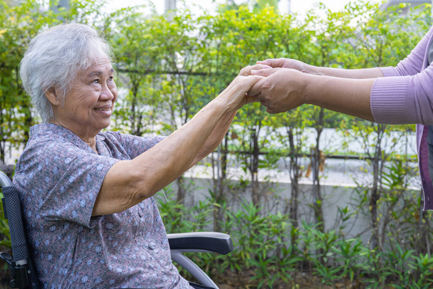 Tomando de la mano Asiática senior o anciana anciana mujer paciente con amor, cuidado, alentar y empatía en el parque. - Foto, imagen