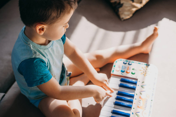 Маленький мальчик веселится, играя на пианино в свободное время. Понятие хобби. Концепция образования. - Фото, изображение