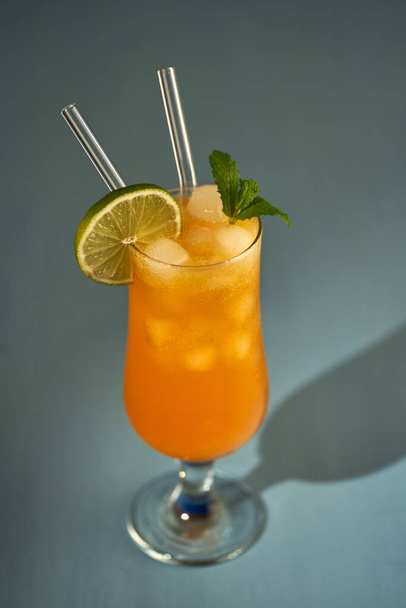 Orange non alcoholic cocktail with ice, a refreshing summer drink on blue - Foto, Imagem