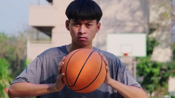 Giovane atleta asiatico in possesso di basket a corte all'aperto. - Filmati, video