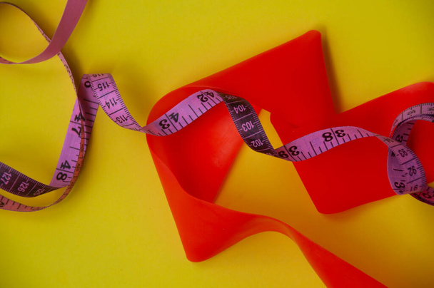 Vista superior de la curva elástica y cinta métrica sobre fondo amarillo - Concepto de fitness y pérdida de peso - Foto, Imagen
